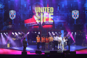 United Hatzalah volunteers stand together with a woman who they saved at the Jerusalem United Hatzalah concert in Jerusalem on Chol Hamoed Peasach. (Credit David Leff: United Hatzalah)