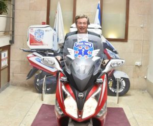 Toronto Mayor John Tory sits astride an ambucycle, the signature vehicle of the organization during his visit to United Hatzalah headquarters.
